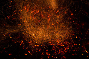 Fototapeta na wymiar Burning fire in the night. Flame and fire sparkles on a dark abstract background. Hellish element of fire. Fuel, power and energy