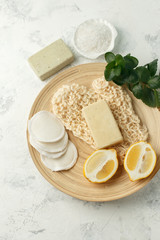 Top view of organic spa skincare bodycare products - lemon, sea salt, soap, zero waste sponge, massage gloves on wooden plate - minimal stylish spa wellness background