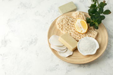 Shower accessories - massage brush, sponge, lemon, sea salt, soap on a light background, top view. Cleansing of the skin, scrub, anti-cellulite health concept.