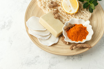 Home beauty products - turmeric, soap, scrub, sponges, lemon, soap, facial brush on light background, top view. Skin youthfulness, beauty concept. Flat lay