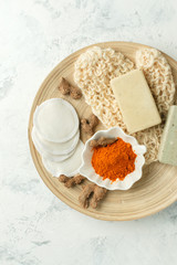 Home beauty products - turmeric, soap, scrub, sponges, soap, facial brush on light background, top view. Skin youthfulness, beauty concept. Flat lay