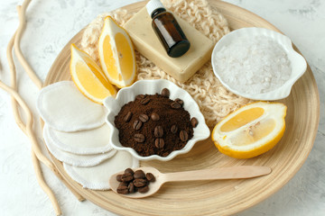 Set for anti-cellulite procedures massage. Coffee scrub, coffee grains, sea salt, lemon, essential oil, soap and sponge on wooden plate and gray background, wellness concept