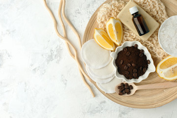 Set for anti-cellulite procedures massage. Coffee scrub, coffee grains, sea salt, lemon, essential oil, soap and sponge on wooden plate and gray background, wellness concept