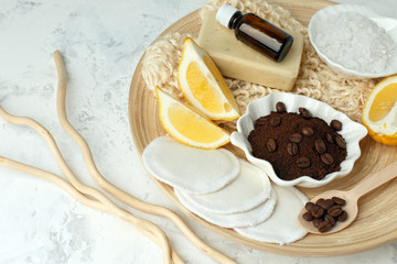Aroma spa set. Coffee scrub, coffee grains, coffee spa salt, lemon, essential oil, soap on wooden plate and gray background top view copyspace, wellness concept