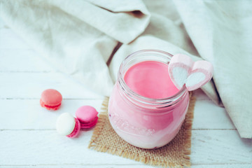 Obraz na płótnie Canvas Pink milkshake with heart shape marshmallows on wood background