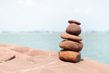 Rock stack on the stone courtyard with blur sea and sky background on the sunshine day. Balance stones against the sea.