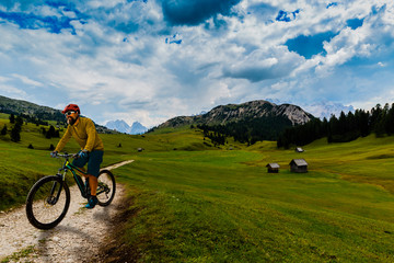 Obraz premium Single mountain bike rider on electric bike, e-mountainbike rides mountain trail. Man cycling on bike in Dolomites mountains. Cycling e-mtb enduro trail track. Outdoor sport activity.