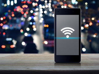 Wi-fi connection flat icon on modern smart mobile phone screen on wooden table over blur colorful...