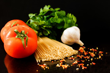  Raw pasta with vegetables and spices, macaroni ingredients on black background