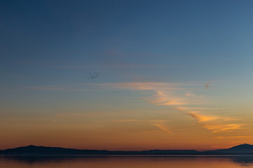 Beautiful view of Trasimeno lake (Umbria, Italy) at sunset, with orange and blue tones in the sky