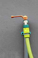 red tab water with green hose on grey wall