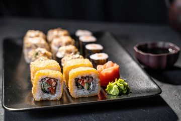 Delicious sushi rolls served on black table with chopsticks