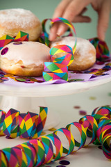 Frau isst traditionelle Deutsche Berliner Pfannkuchen Krapfen zu Fasching, Karneval oder Silvester mit bunten Konfetti und Luftschlangen