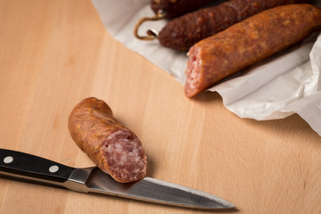 Ringwurst Salami und Bierbeißer Wurst in Wachspapier mit Messer auf Vesper Holzbrett