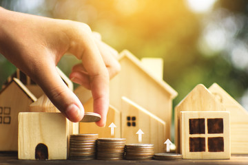 Female hands protection the little wood house model on plank and tree bokeh background, start to plan and saving money for residential .