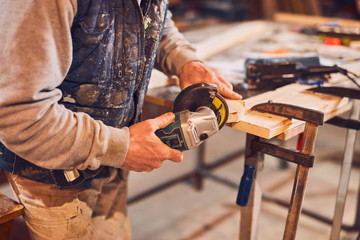 Male carpenter working on old wood in a retro vintage workshop.