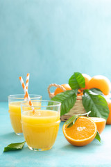 Orange freshly squeezed juice in glass and fresh fruits on a blue vivid background