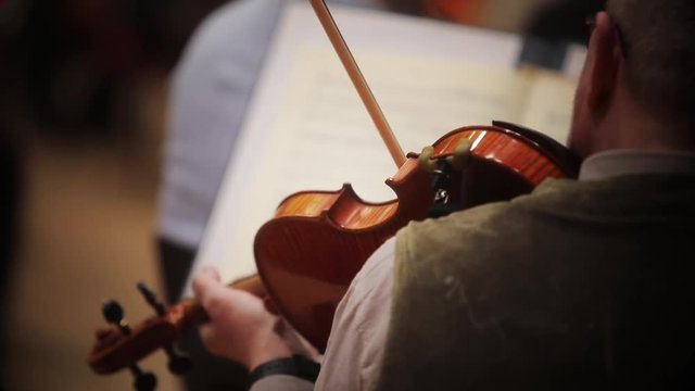 Close up footage of a person performing on a violin during a concert.