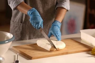 Woman cutting tasty cheese on wooden board