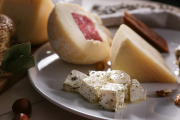 Plate with assortment of tasty cheese on table, closeup