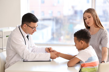 Obraz premium Pediatrician examining African-American boy in clinic