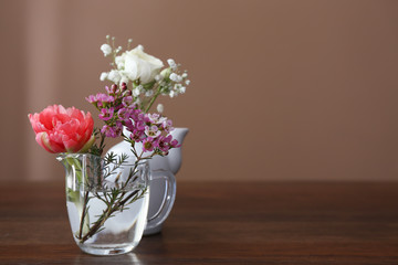 Vases with beautiful flowers on table