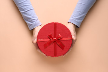 Female hands with gift box on color background