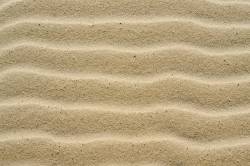 Fototapeta na wymiar Textured background of beautiful wavy yellow sea sand.