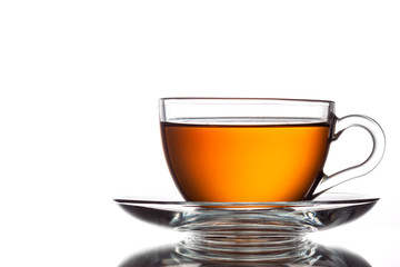 A cup of black tea and a spoon on a white table with reflection