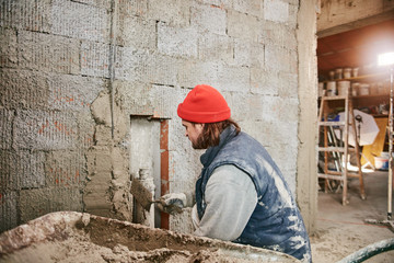 Real construction worker making a wall inside the new house.
