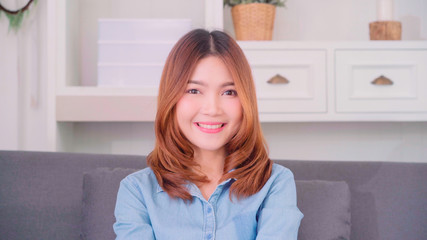 Naklejka premium Teenager Asian woman feeling happy smiling and looking to camera while relax in her living room at home. Beautiful Asian young female using relax time at home concept.