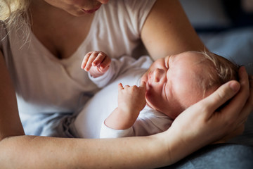 A midsection of mother with a sleeping newborn baby at home.