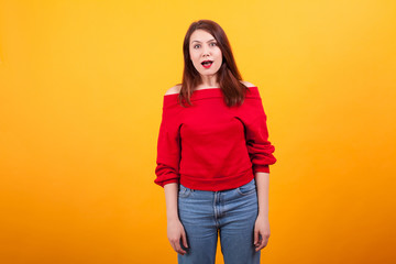 Portrait of confused beautiful young woman over yellow background