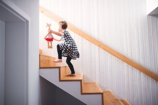 A Small Child With A Soft Toy Walking Up The Stairs.