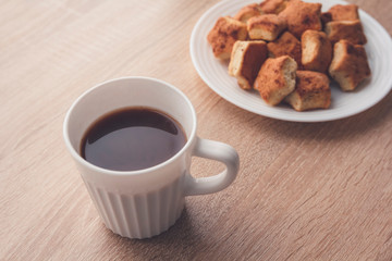 A lot of newly-baked cookies with cinnamon on white plate. Cup of coffee