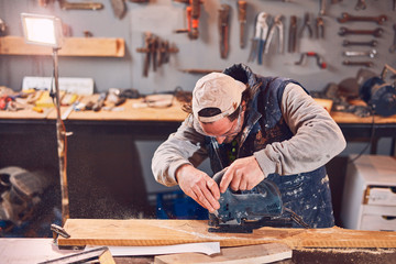 Male carpenter working on old wood in a retro vintage workshop.