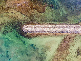 Aerial view of a stone breakwater at Marineta Beach, in Denia, Spain