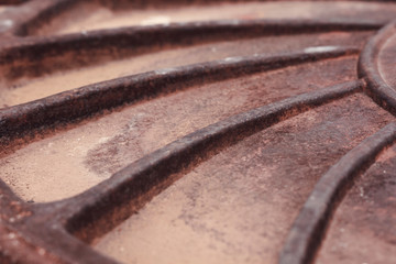 Rusty manhole cover with a spiral pattern