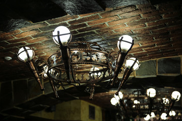Fototapeta na wymiar Medieval lamp on the ceiling. Knight style chandelier decoration. Restaurant exterior.