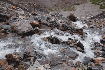 Waterfall in a high gorge among the brown rocks and fog of the Altai mountains.