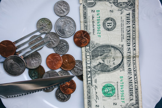 One dollar lying on the plate with fork and knife. No money photo. Poor people idea. Dimes and cents coins. Small salary and pension not enough for food. Social problems.