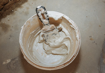 Mixing spackling paste putty in the bucket. Grind of wall. Maintenance repair works renovation in...