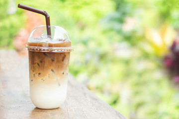 iced coffee latte with milk in plastic cup on wooden table outdoor cafe 