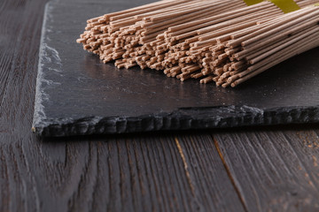 Dried buckwheat soba noodles on rustic wooden board