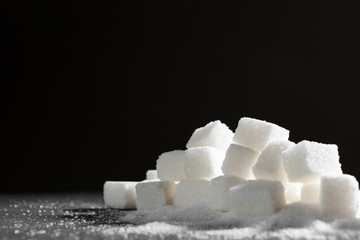 Sugar lumps piled up together against a black background