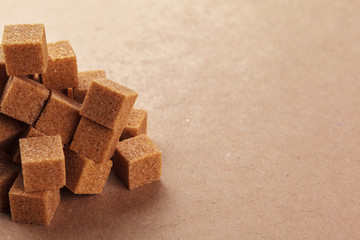 Brown cane sugar cubes on a light brown background