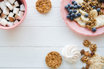 Healthy tasty snack on white wooden table, copy space for text. Fruit pieces in coral color plates, natural cookies with oat and nuts. 