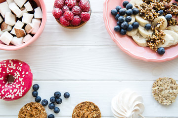 Served table, healthy breakfast: granola with fresh blueberry and banana. Coconut pieces in coral color plates on white wooden table. Space for text. 