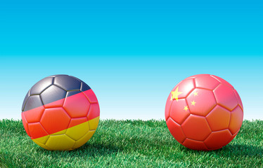 Two soccer balls in flags colors on green grass. Germany and China. 3d image