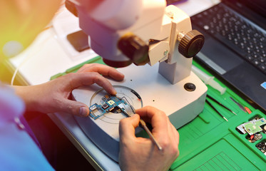 technician repairing the smartphone's motherboard in the lab with copy space. the concept of...